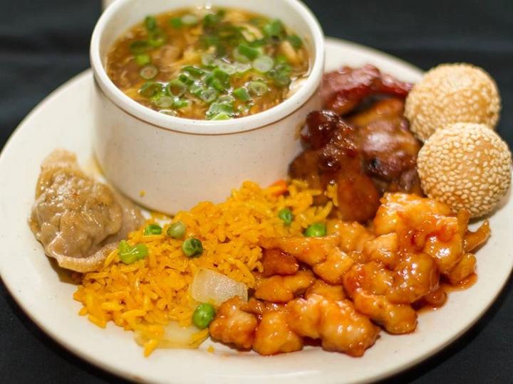 A plate of soup, fried rice, sesame balls, dumplings and sweet and sour chicken