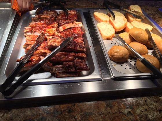 Barbecue spare ribs next to a tray of buttery rolls