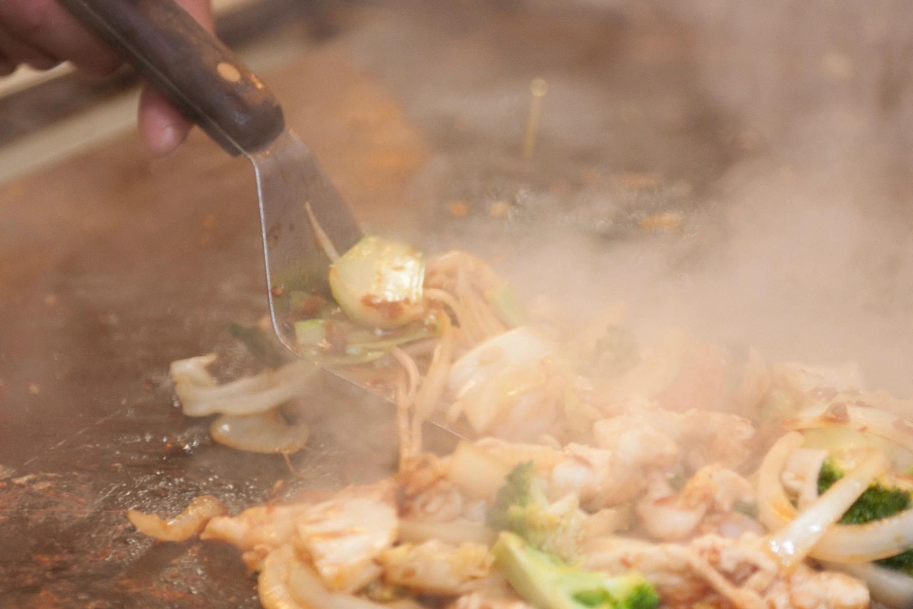 A chef stir-frying meat and vegetables on the Mongolian grill